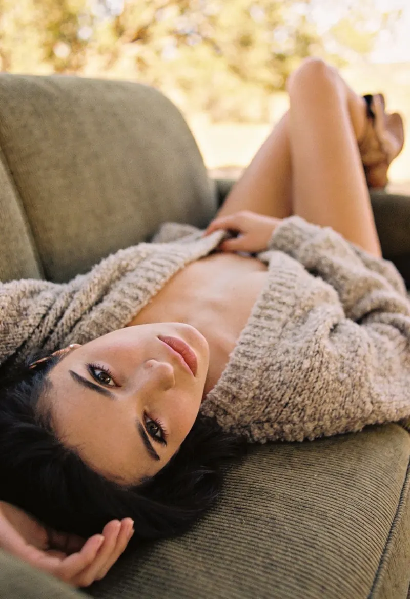 Auburn-haired woman relaxing on a couch in warm evening light